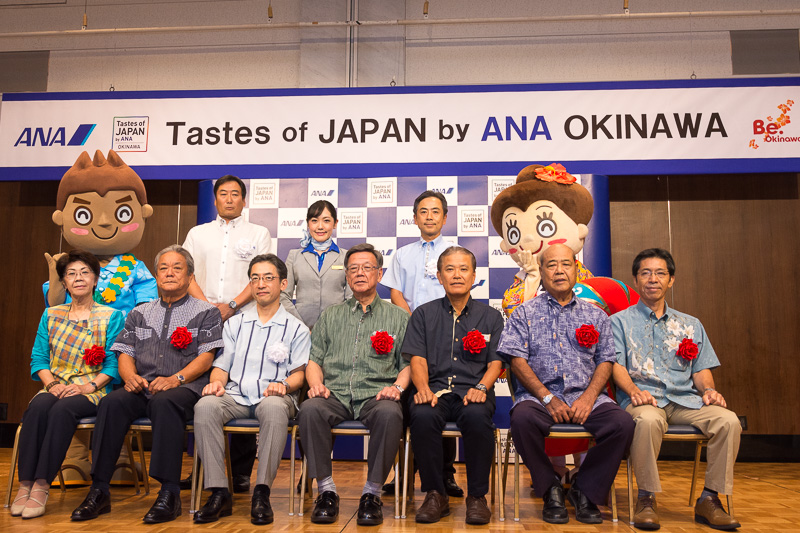 記者発表会の参加者。前列左から、沖縄県酒造組合 会長 玉那覇美佐子氏、一般財団法人八重山ビジターズビューロー 副会長 外間守吉氏、全日本空輸株式会社 代表取締役社長 平子裕志氏、沖縄県知事 翁長雄志氏、一般財団法人沖縄観光コンベンションビューロー 専務理事 前田光幸氏、一般財団法人宮古島観光協会 会長 豊見山健児氏、一般財団法人沖縄美ら島財団 常務理事 親川達男氏。後列左から、沖縄観光PR大使 マハ朗くん、全日本空輸株式会社 沖縄支社 支社長 近藤博之氏、坂口CA、全日本空輸株式会社 執行役員 九州支社 支社長 宮川純一郎氏、沖縄観光PR大使 花笠マハエちゃん