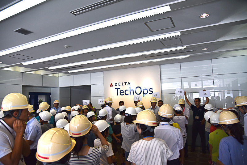 「デルタ・テックオプス（Delta TechOps）」のロゴ前で同社スタッフに挨拶