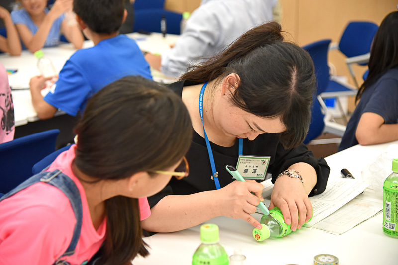 ドリンクのラベルの上部に沿ってチームリーダーがカット