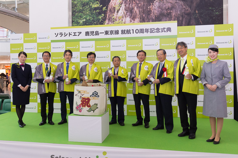 鏡開きの樽の中には霧島町の「関平鉱泉水」。鏡開きを行なったのは右から順に株式会社ソラシドエア 代表取締役社長 髙橋宏輔氏、鹿児島空港ビルディング株式会社 代表取締役社長 渡邉勝三氏、鹿児島県商工会議所連合会 常任幹事 山下春洋氏、霧島市 市長 前田終止氏、鹿児島県 副知事 岩切剛志氏、国土交通省 大阪航空局 鹿児島空港事務所 空港長 佃健次氏、株式会社ソラシドエア 取締役 西尾敏氏