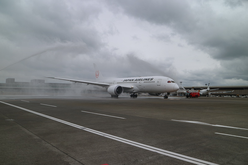 ボーイング 787-8型機はゆっくりと発進。あいにくの曇天と強風ではあったが、両脇の消防車が描くアーチをくぐっていく