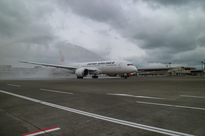 ボーイング 787-8型機はゆっくりと発進。あいにくの曇天と強風ではあったが、両脇の消防車が描くアーチをくぐっていく