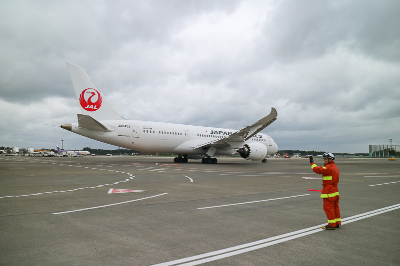 ボーイング 787-8型機はゆっくりと発進。あいにくの曇天と強風ではあったが、両脇の消防車が描くアーチをくぐっていく