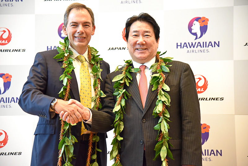 笑顔で固い握手をする日本航空株式会社 代表取締役社長 植木義晴氏とハワイアン航空 代表取締役社長 兼CEO マーク・ダンカリー（Mark B. Dunkerley）氏