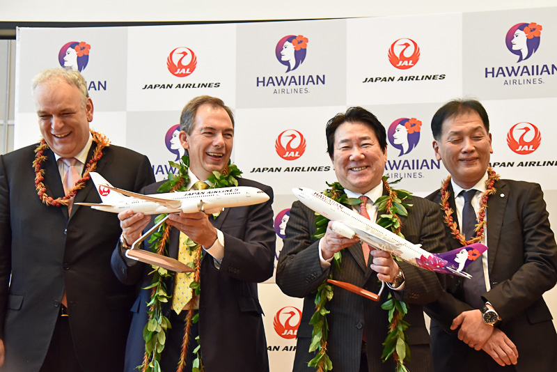 包括的業務提携契約に合意したことを祝いパネルに代表らが笑顔でサイン