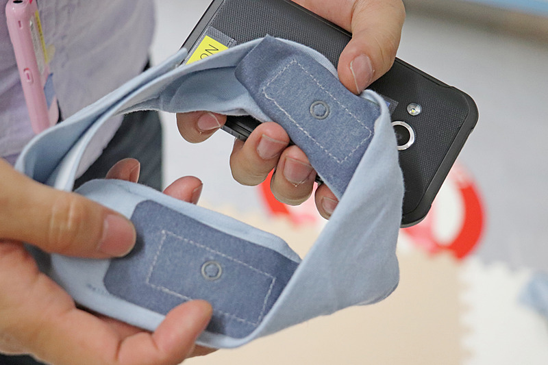 グレーの電極付きの小さな布2カ所が、東レが開発した赤ちゃん用の機能素材「hitoeウェア」。体の前後を挟んで測定する