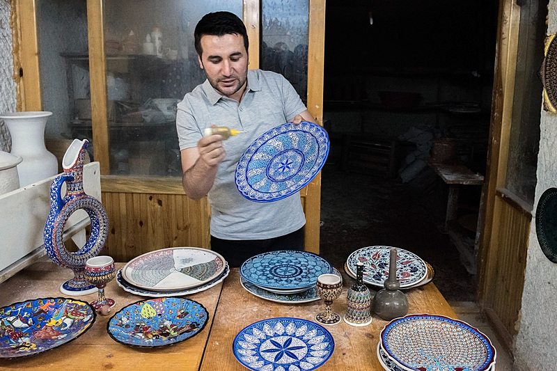 点描の文様は、店主が手に持っているスポイトのような道具で丁寧に彩色される。机の上には、チューリップやカーネーション、オスマン帝国のスルタン、生命の樹といった定番の柄の皿が並ぶ