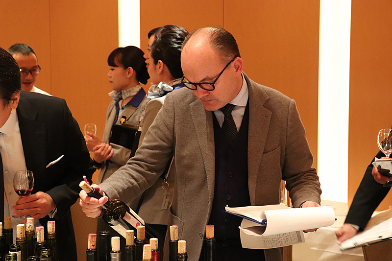 ブラインドテイスティング用のカバーが外されたワインをチェックするプーシエ氏