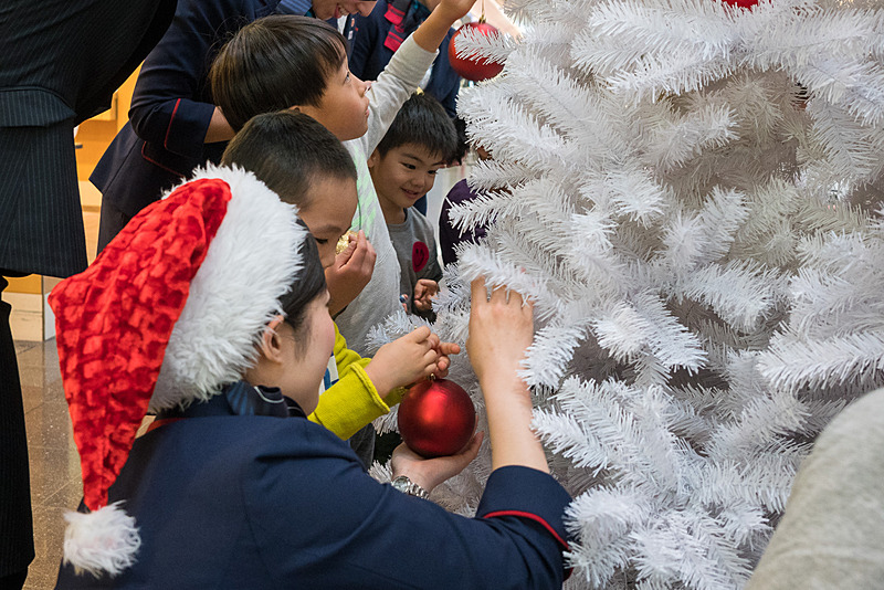 大きなクリスマスツリーへゴールドや赤色のボールを楽しそうに飾り付け