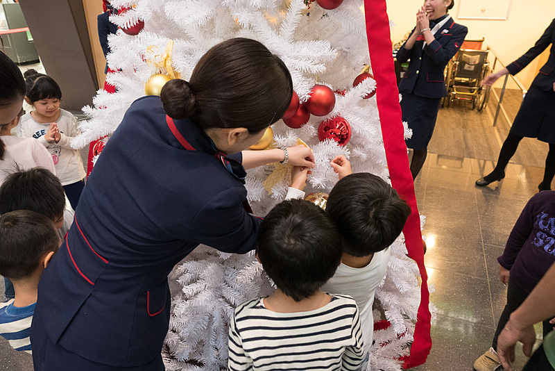 大きなクリスマスツリーへゴールドや赤色のボールを楽しそうに飾り付け