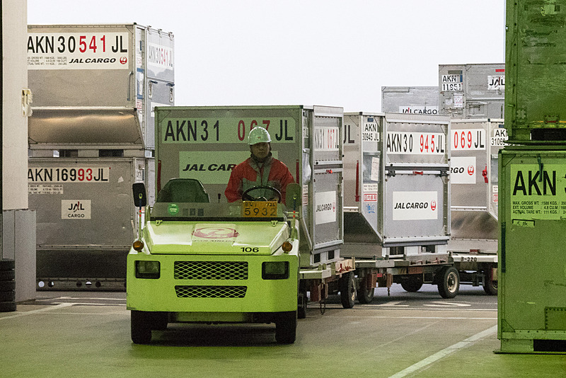 トーイングトラクターに乗って、博多万能ねぎが入ったコンテナが貨物エリアへ運ばれてくる