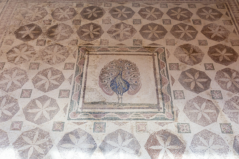 幾何学模様の中心にクジャクが立つ。天然石ながらクジャクの色彩が見事