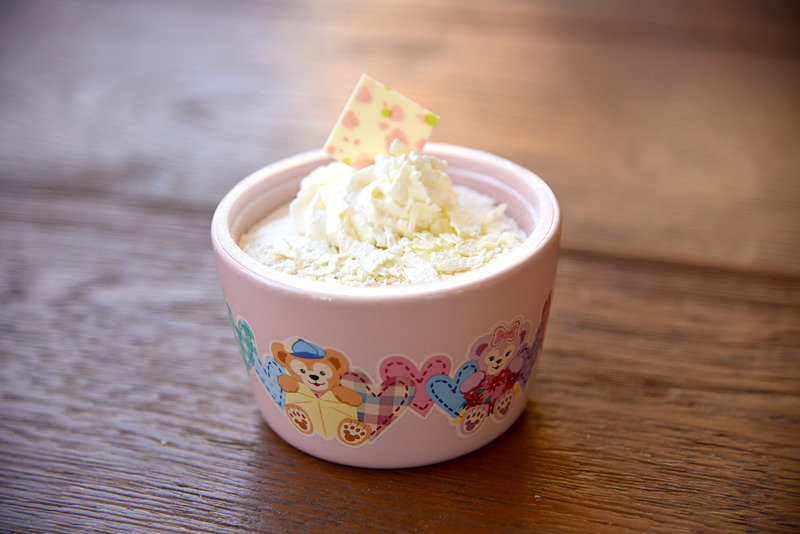 「ミルクティームース、スーベニアカップ付き」（880円）。ちょうどよい深さのカップにはそれぞれのプレゼントを抱きしめる4人の姿が描かれている