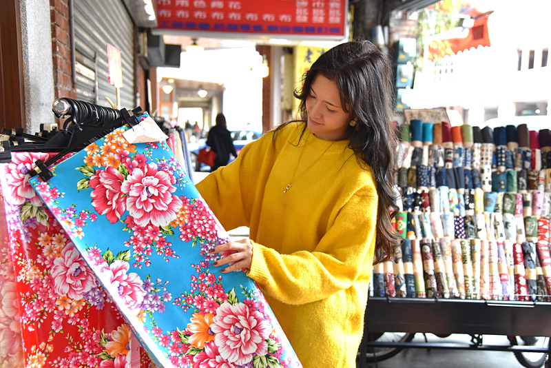 鮮やかな色合いの客家布を手にするFukiさん。気になる柄は見付かりましたか？