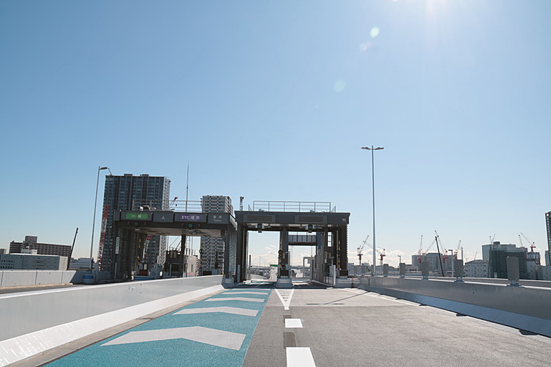 10号晴海線の豊洲入口と晴海入口は並んでいる。現在の路面のマーキングは豊洲入口側が主線となっているが、追々は晴海入口側を主線に変更するとのこと。東京湾に向かって右手に見えるクレーン群は、2020年東京オリンピック・パラリンピックの競技場の建設機材