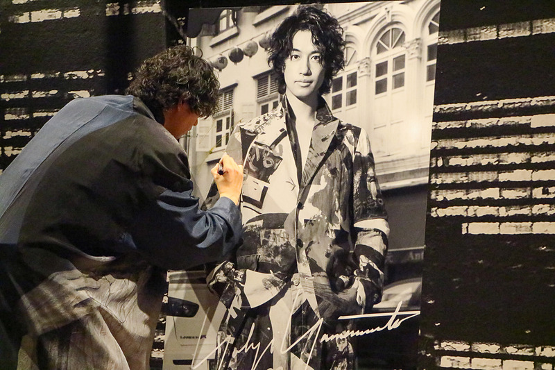 レスリー・キーさんが撮影した写真パネルに斎藤工さんがサイン