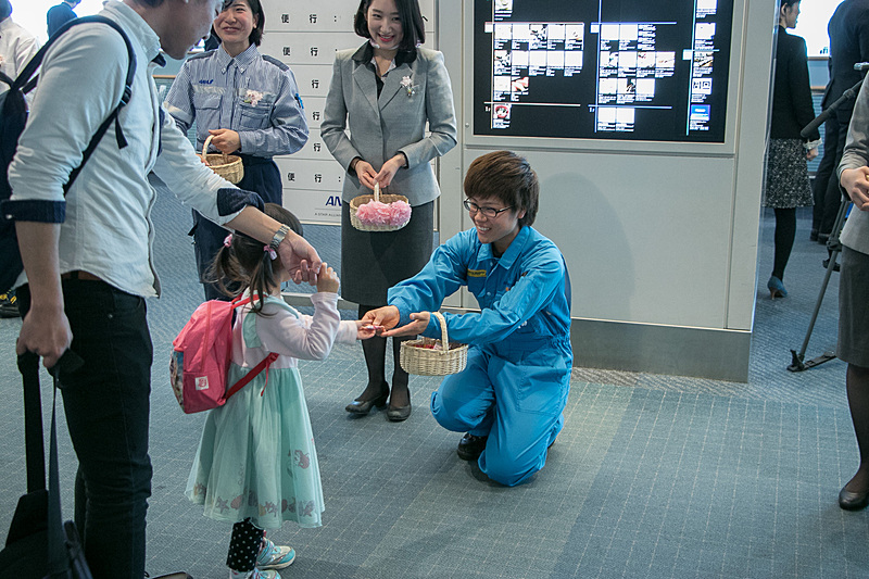 ANAグループ各部門の女性スタッフが、乗客にお菓子を配る