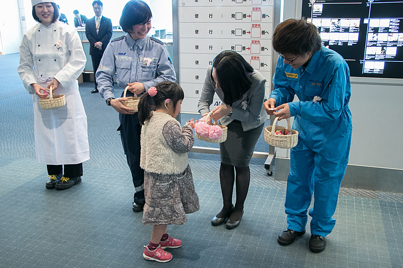 ANAグループ各部門の女性スタッフが、乗客にお菓子を配る