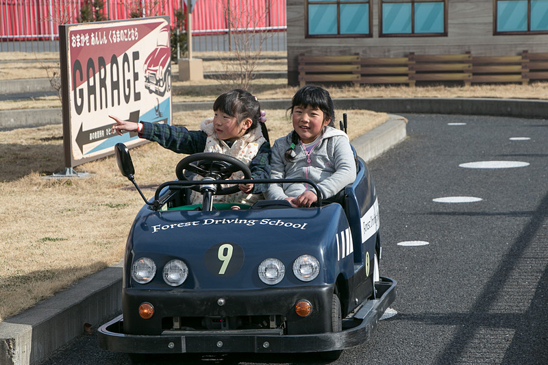 市街地コースをドライブしながら交通ルールを学ぶ「森の教習所」。「止まれ」の標識では一時停止して安全を確認