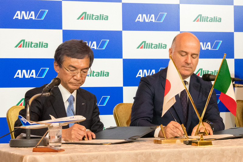 包括提携契約の書類にサインをする両名