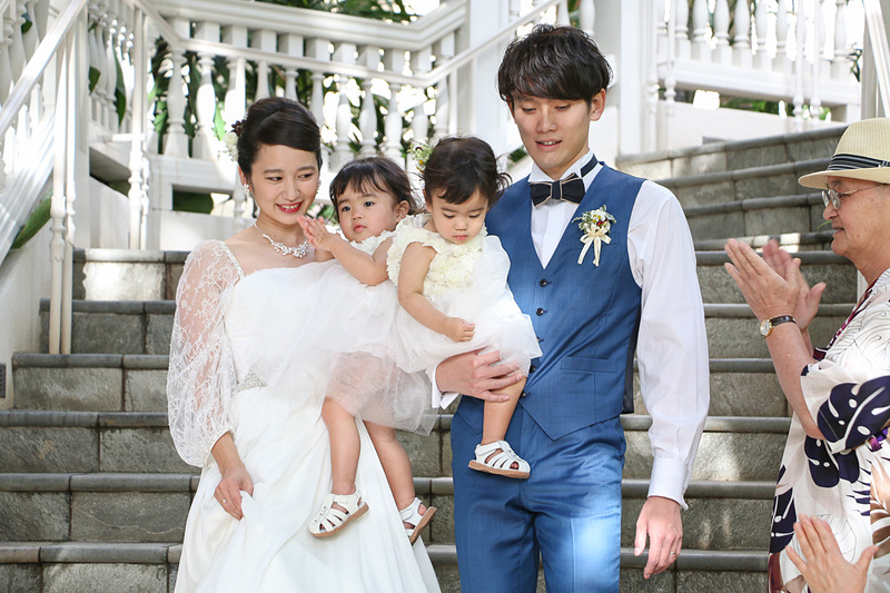 ゲストに祝福され、子供たちを抱いて大階段を歩く2人