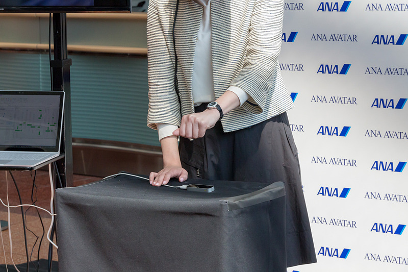 株式会社メルティンが取り組んでいる「ANA AVATAR DIVING」のブース。操作者の手元にあるカメラの上で手を動かしたり握ったりすると、その動きを分析して水槽内のマニピュレータ同じように動作して貝をつかめる