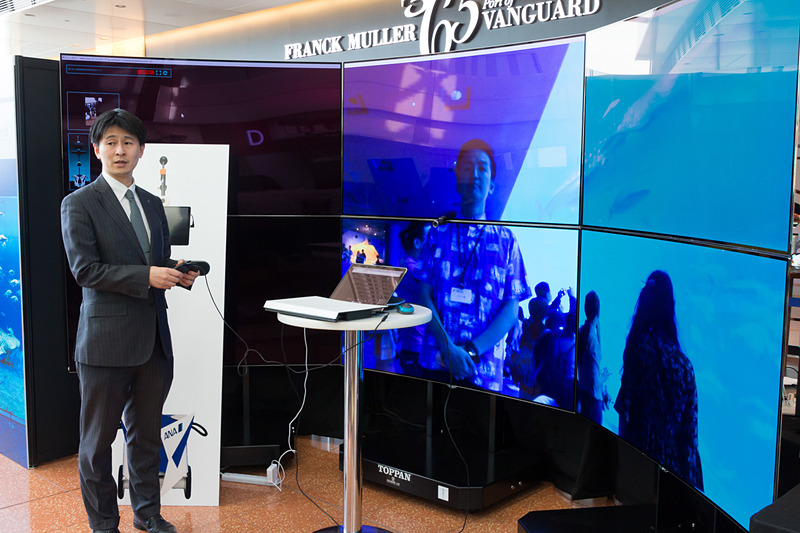 凸版印刷株式会社が取り組んでいる「ANA AVATAR MUSEUM」のブース。当日は沖縄県にある美ら海水族館の大水槽前にあるアバターが撮影している4K映像をリアルタイムで大画面に表示していた。コントローラでアバターの向きを変えることで視野も変化する