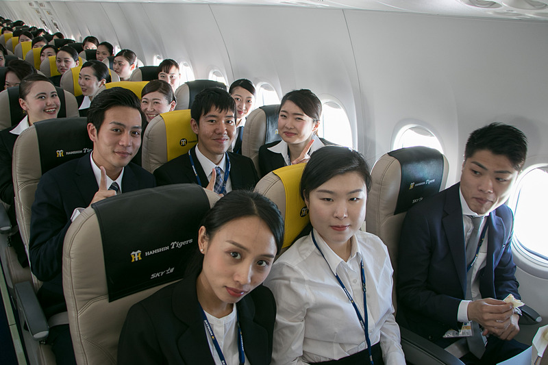 配られたサンドイッチのお弁当を食べながら空の旅を楽しむ新入社員。お世話になった人事部長との記念撮影を求める人も多かった