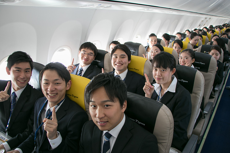 配られたサンドイッチのお弁当を食べながら空の旅を楽しむ新入社員。お世話になった人事部長との記念撮影を求める人も多かった