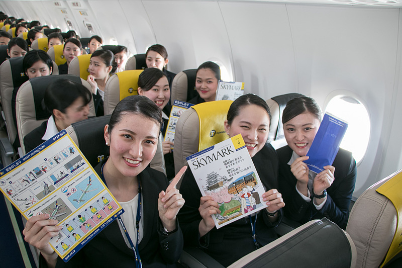 配られたサンドイッチのお弁当を食べながら空の旅を楽しむ新入社員。お世話になった人事部長との記念撮影を求める人も多かった