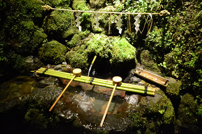 本宮社殿前の石垣から湧き出る神水。無料で飲むことができ、多くの人が水を汲みにくる