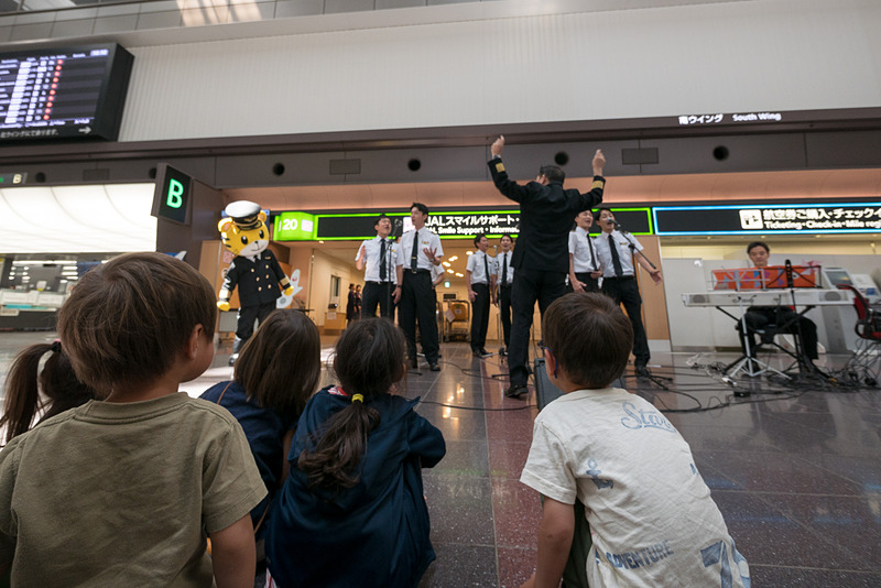 JALスマイルサポート前でのパフォーマンスでは子供を中心に多くの人が見学。パイロットから子供たちにシールが送られた。普段は乗客と接する機会が少ないパイロットにとっても貴重な機会になっている