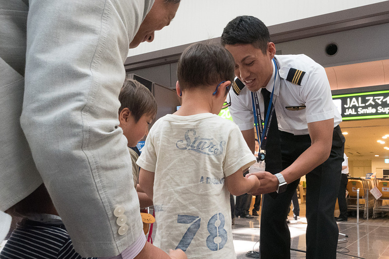 JALスマイルサポート前でのパフォーマンスでは子供を中心に多くの人が見学。パイロットから子供たちにシールが送られた。普段は乗客と接する機会が少ないパイロットにとっても貴重な機会になっている