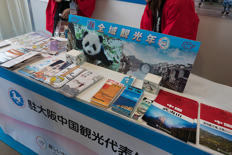 在大阪中国観光処のブースでは観光パンフレットを展開。お茶のふるまいなどのステージイベントも実施していた