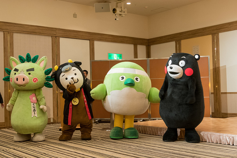 各県代表者のあいさつに際してご当地キャラも登場。左から鹿児島県の「グリブー」、宮崎県の「みやざき犬ひぃくん」、大分県の「めじろん」、熊本県の「くまモン」