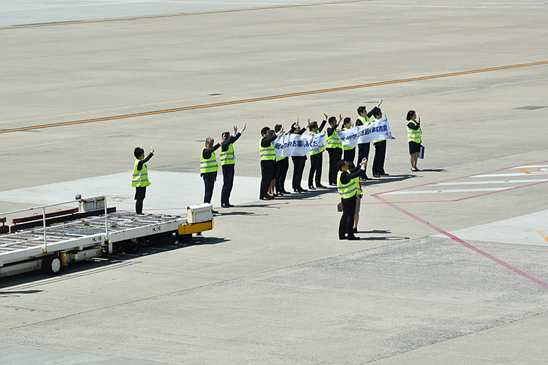 地上から手を振るANA福岡空港支店のスタッフ