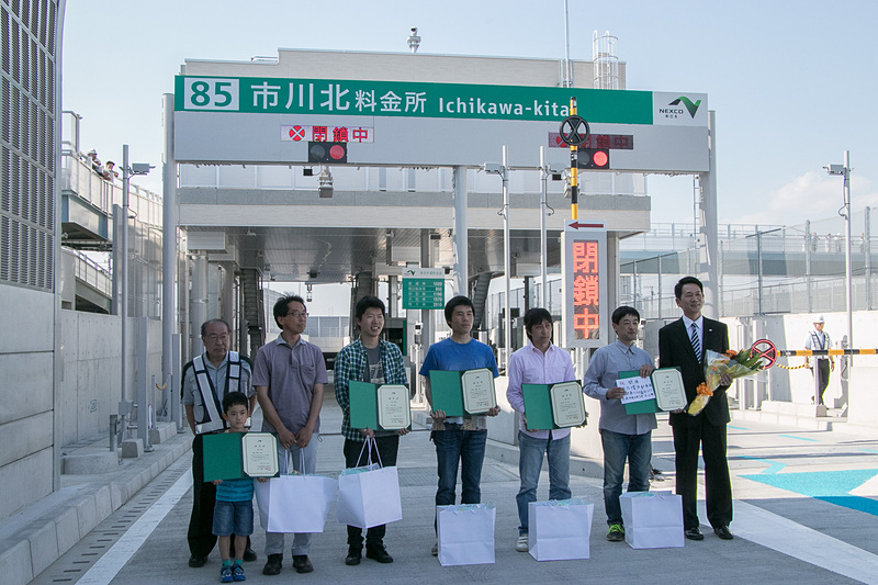 外環道 三郷南IC～高谷JCT間が6月2日16時に開通することを記念して、開通時刻の16時前に市川北料金所のゲート前で営業開始セレモニーと、利用者「一番乗り」への記念品贈呈式を行なった