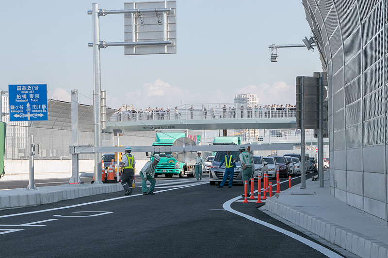 開通時刻を過ぎ、料金所への道には早くも長い車列ができる。少し間を置いて一般車両が入場できるようになった