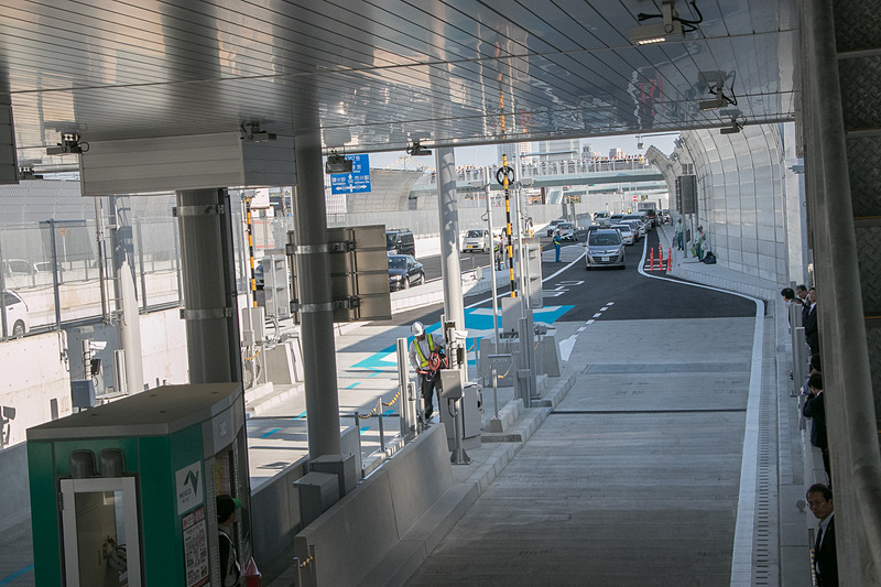 開通時刻を過ぎ、料金所への道には早くも長い車列ができる。少し間を置いて一般車両が入場できるようになった