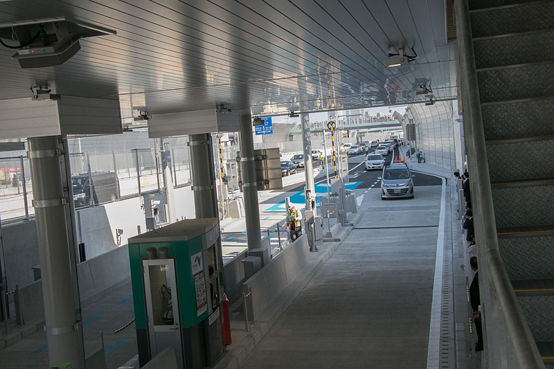 開通時刻を過ぎ、料金所への道には早くも長い車列ができる。少し間を置いて一般車両が入場できるようになった