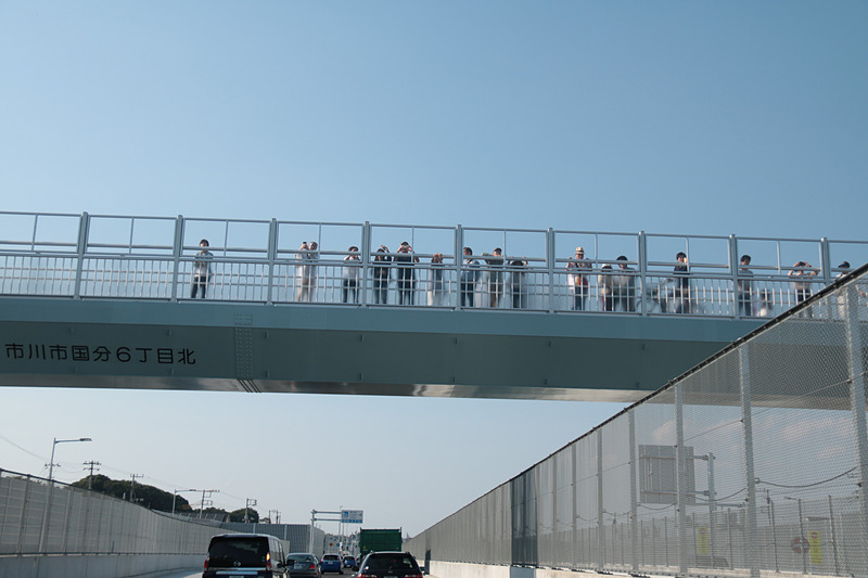 実際には自動車専用道部分はシェードにより遮られていて歩道橋から覗き込むことはできないのだが、どの歩道橋も開通した外環道と国道298号を眺める人々が多かった。単なるひとつの公共事業ではなく、地域の人々にとって数十年越しの念願だった道路の開通ではあるが、これだけの老若男女が歩道橋に集まるのを筆者は今までに知らない