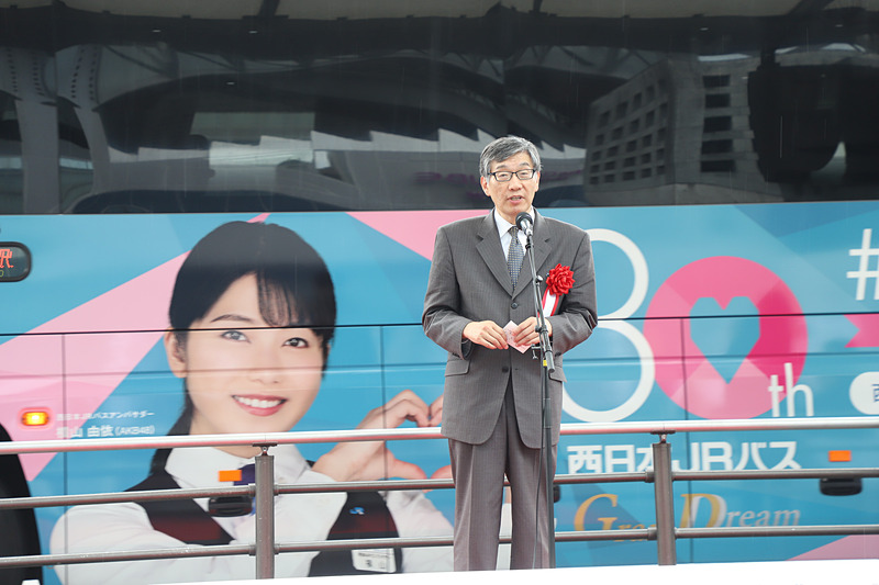 あいさつする加瀬氏。このとき1番のりばにラッピングバスが到着した