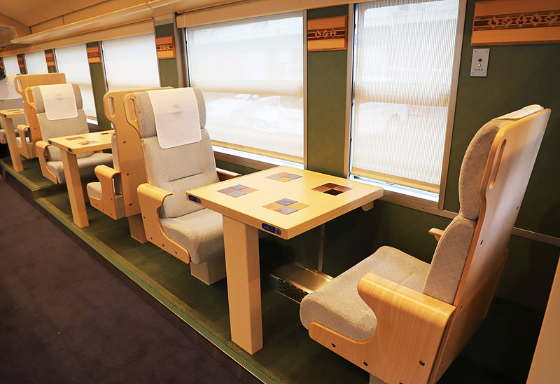 1号車（写真左）、2号車（写真右）ともに山側（奇数番号席）は2名掛けの対面シート。海が見えやすいように床面より一段高くなっている