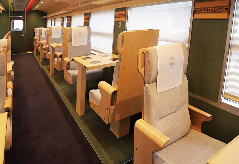 1号車（写真左）と比較して2号車（写真右）の対面シートの一部は、さらに一段高くなっている。鳥取県をイメージした2号車のみの通称「大山シート」だ