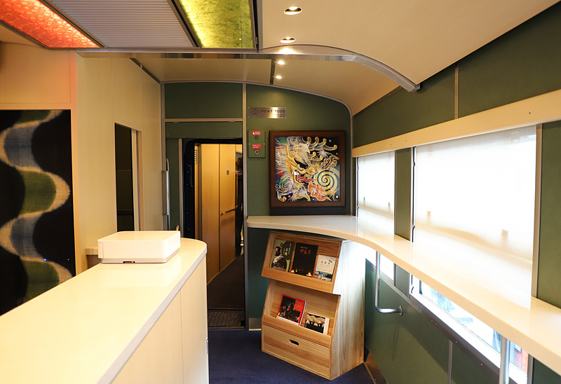 2号車にはカウンターがある。乗客が予約した弁当の準備などを行なうほか、ドリンクや山陰の菓子類、「あめつち」オリジナルグッズなども販売する。左端ののれんは西尾絞り（鳥取市）だ