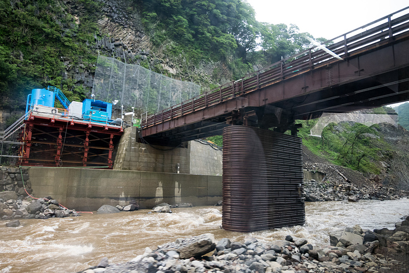 ダムは奥に見える低い仮設橋の位置に建設。堤の長さ（幅）は約200m、高さは約90mとなる。ここに約5m四方の穴が開けられ、常時水が流れる穴あきダムとなる