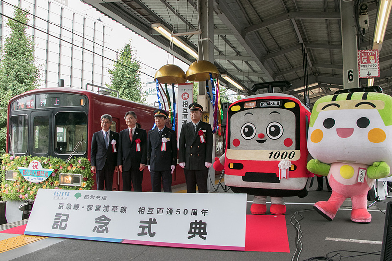 京急は品川駅3番線ホームにおいて、京急と東京都交通局・都営浅草線との「相互直通50周年記念式典」を開いた。左から京浜急行電鉄株式会社 取締役社長 原田一之氏、東京都交通局 局長 山手斉（ひとし）氏、京急 品川駅長 入江哲哉氏、東京都交通局 大門駅務管区長 安達武司氏