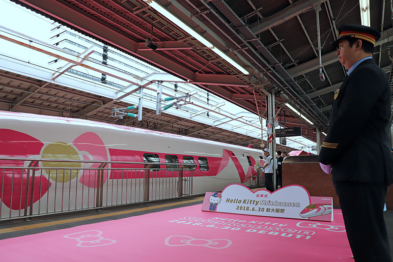 ハローキティのリボンをモチーフにしたピンクの新幹線がホームに滑り込む