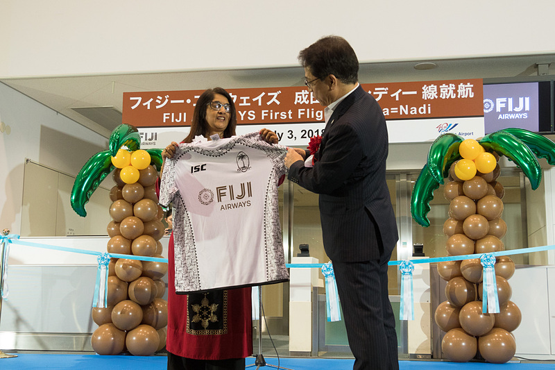 フィジー・エアウェイズのシェナーズ・ヴォス氏からNAAの荒川武氏へ、フィジー・エアウェイズのロゴと「350」便を背番号にデザインしたTシャツをプレゼント