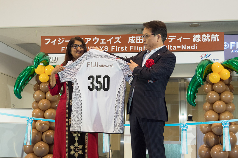 フィジー・エアウェイズのシェナーズ・ヴォス氏からNAAの荒川武氏へ、フィジー・エアウェイズのロゴと「350」便を背番号にデザインしたTシャツをプレゼント